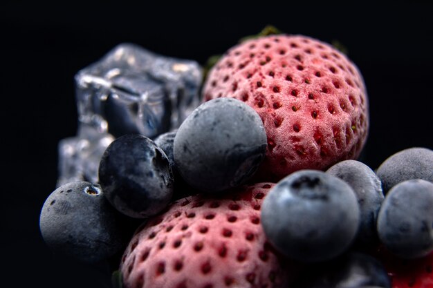 Macro vista delle bacche congelate: fragola, mirtillo con cubetti di ghiaccio