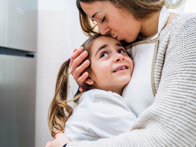 Madre adorabile che bacia la sua piccola figlia sveglia a casa