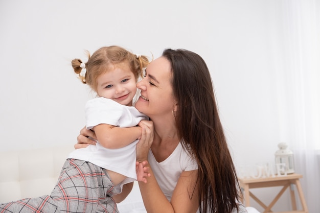 madre adulta che abbraccia la sua piccola figlia a casa, divertendosi.