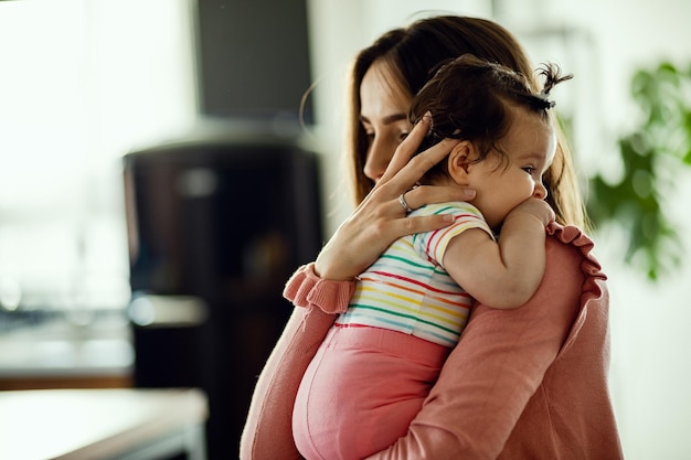 Madre affettuosa che abbraccia la sua bambina mentre la tiene a casa Focus è sul bambino