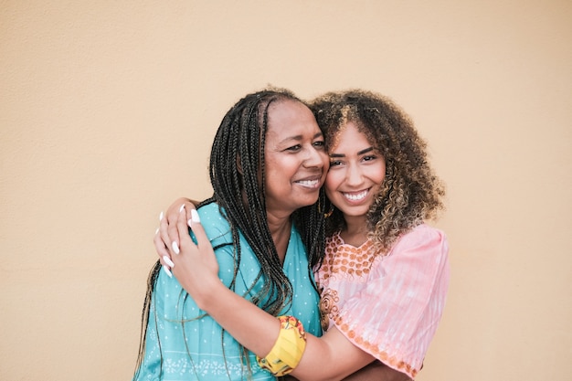 Madre afroamericana che abbraccia la figlia adulta di razza mista - Family love