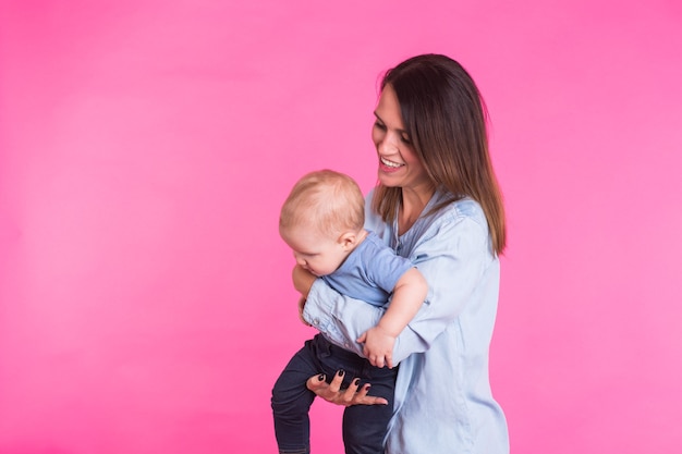 Madre amorevole che gioca con il suo neonato in rosa.