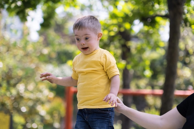 Madre amorevole che tiene la mano del figlio piccolo in maglietta gialla per aiutare la struttura rampicante