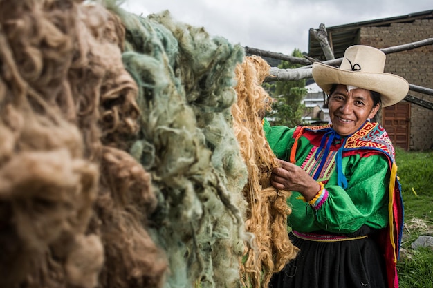 Madre andina latinoamericana che asciuga lana colorata per la tecnica Inca di tessitura della vita peruviana