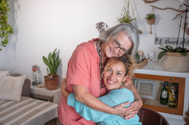 Madre anziana caucasica e figlia matura che si abbracciano mentre trascorrono del tempo insieme a casa Persone sorridenti che provano amore ed emozioni positive