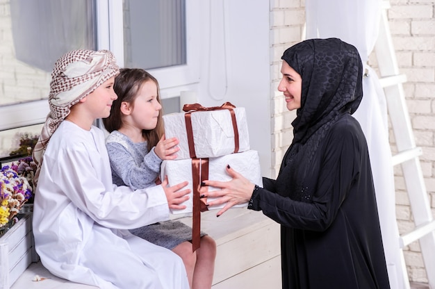 Madre araba e bambini che posano con il regalo.