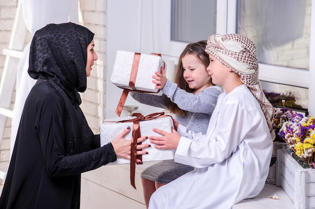 Madre araba e bambini che posano con il regalo.