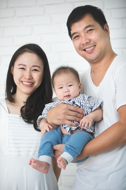 Madre asiatica felice del padre della famiglia con il figlio che guarda macchina fotografica con il fronte di sorriso