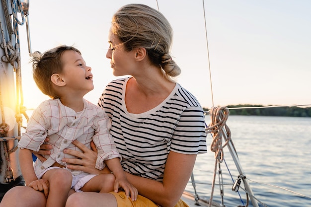 Madre attraente con il suo adorabile figlio piccolo che naviga in mare su una barca a vela