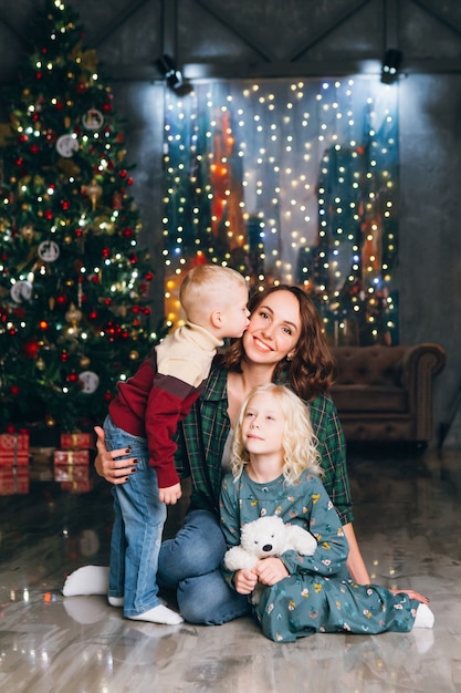 Madre carina con figlia e figlio in posa all'albero di Natale