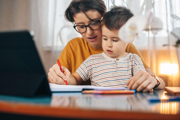 Madre caucasica che insegna al suo bambino che scrive l'alfabeto e numeri mamma che scrive numeri e