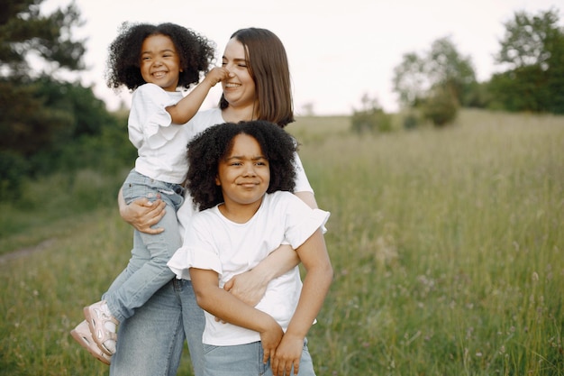 Madre caucasica e due sue figlie afroamericane che si abbracciano insieme all'aperto