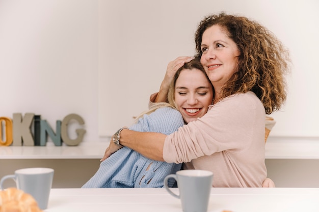 Madre che abbraccia la figlia durante la colazione