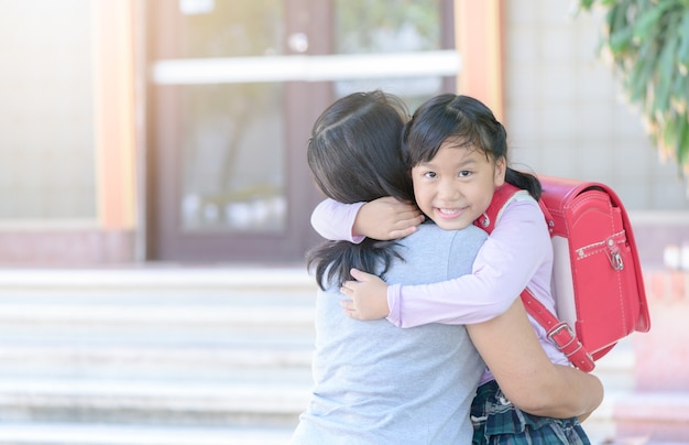 madre che abbraccia la figlia in uniforme studente