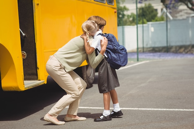 Madre che abbraccia sua figlia con lo scuolabus