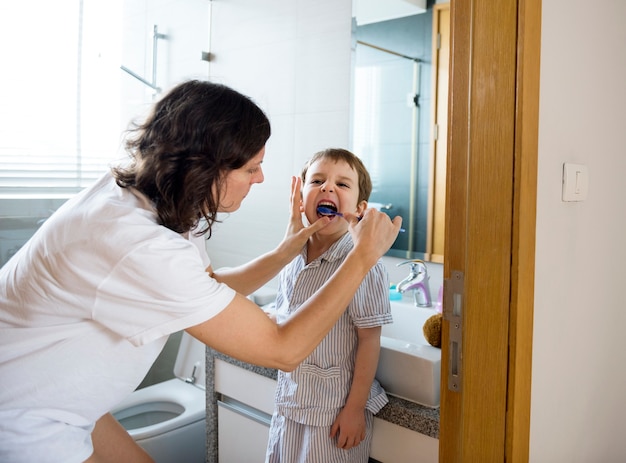 Madre che aiuta il figlio a lavarsi i denti