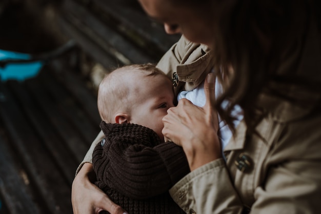 Madre che allatta il suo bambino all'aperto nel parco mentre è seduta sulla panchina