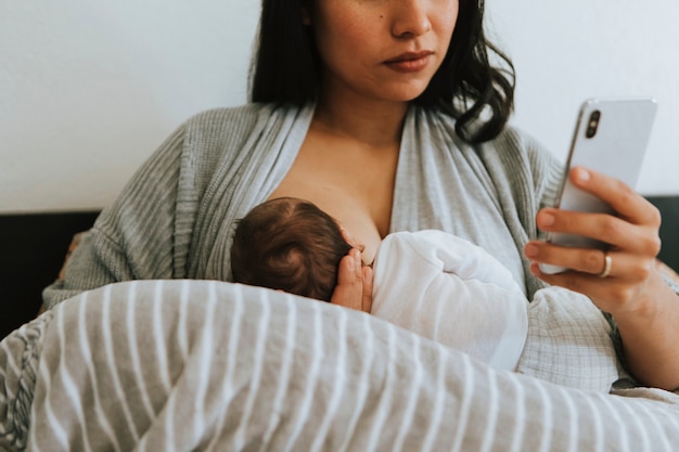 Madre che allatta usando uno smartphone