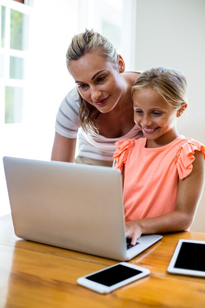 Madre che assiste figlia nel computer portatile uising a casa