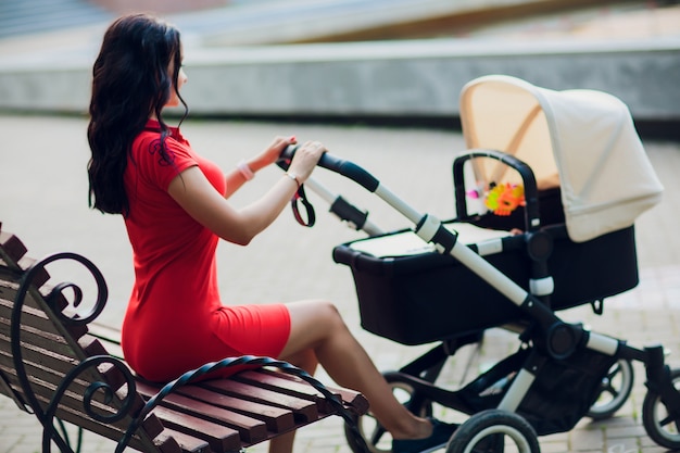 Madre che cammina con passeggino carrozzina, carrozza in città. Amore e concetto di famiglia.