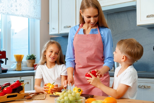 Madre che cucina con i suoi figli in cucina