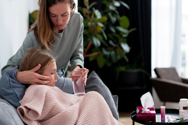 Madre che dà da bere a sua figlia con il raffreddore