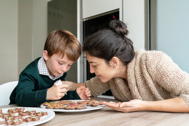 Madre che decora i biscotti di Pan di zenzero con il bambino a casa