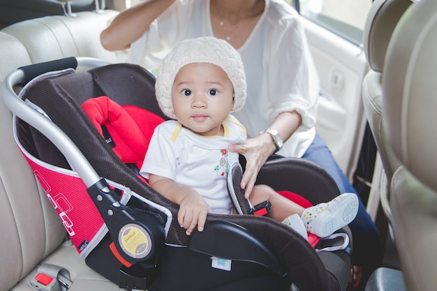 Madre che fissa il suo bambino nel seggiolino auto nella sua auto