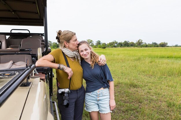 Madre che fotografa con la figlia adolescente vicino al veicolo safari Botswana