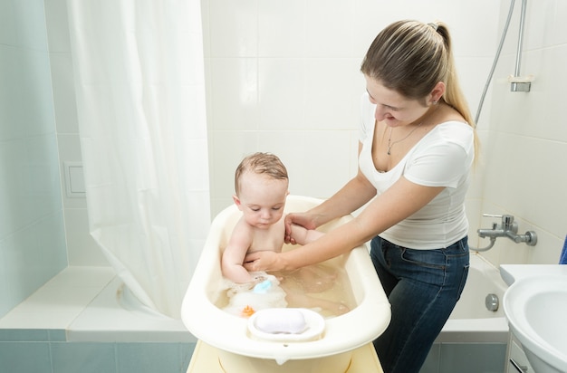 Madre che lava il suo bambino nella vasca da bagno