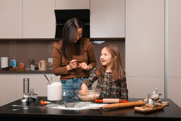 Madre che mette con le dita un po 'di pasta di crema aromatica sul naso della figlia e ride