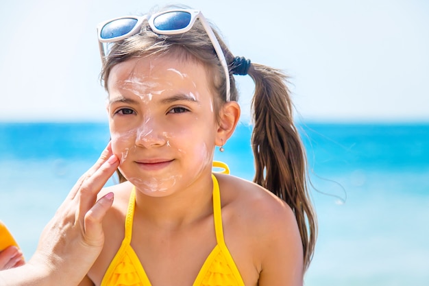 Madre che mette la crema solare sul viso di sua figlia sulla spiaggia