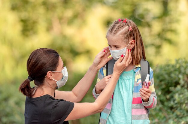 Madre che mette la maschera protettiva sulla piccola figlia prima di tornare a scuola