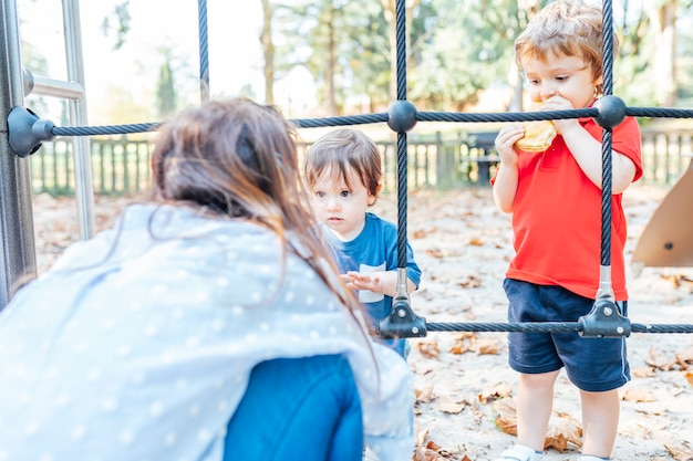 Madre che parla con suo figlio di uno e tre anni delle regole di comportamento nel parco. concetto di educazione