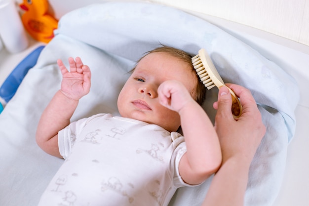 Madre che pettina i capelli per il suo bambino. Concetto di assistenza ai neonati.