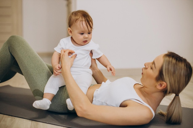 Madre che pratica yoga con la sua bambina a casa