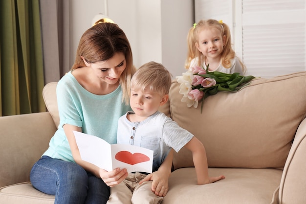 Madre che riceve biglietti di auguri e fiori dai suoi simpatici bambini a casa