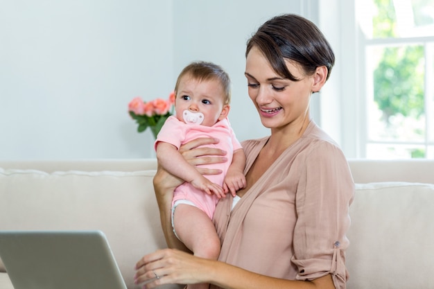 Madre che sorride mentre portando figlio sul sofà