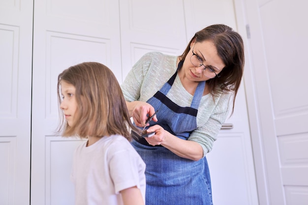 Madre che taglia i capelli alla figlia a casa, bambini, acconciature, capelli, bellezza.