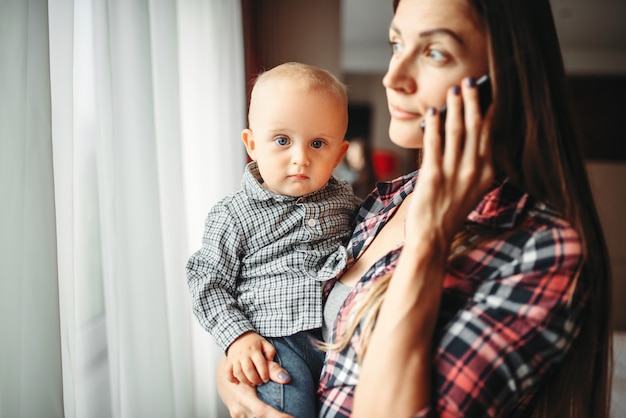 Madre che tiene il bambino in braccio e parla al telefono