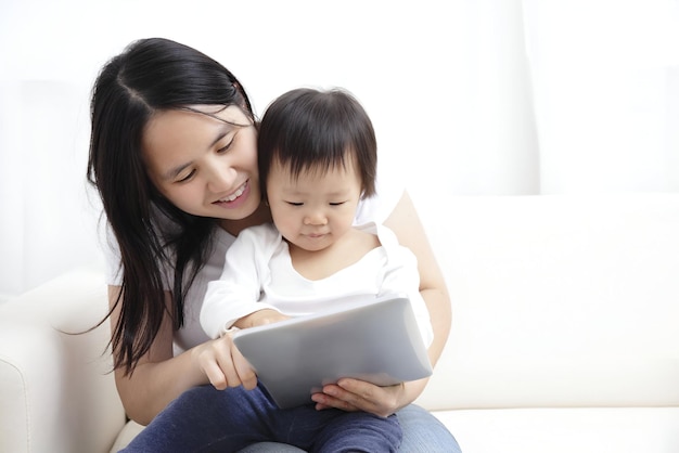 Madre che tiene in braccio il bambino mentre usa il tablet