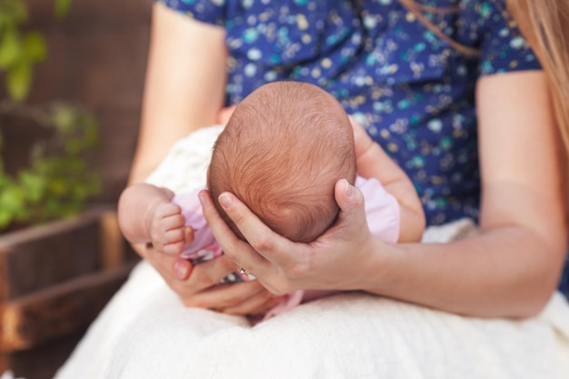 Madre che tiene la testa del figlio neonato nelle mani Il bambino sulle mani alla mamma Mano della madre amorevole che tiene il bambino neonato addormentato carino