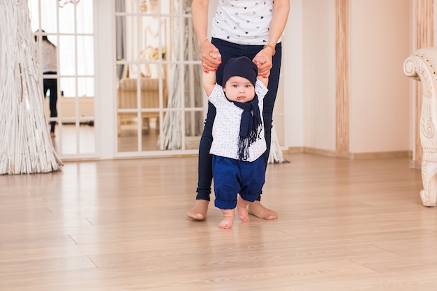 Madre che tiene le mani del bambino per aiutarlo a camminare. Primo concetto di passo.