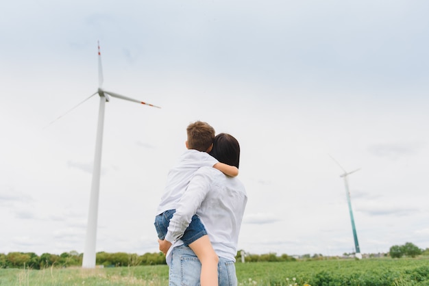 Madre che tiene suo figlio in natura. Turbine eoliche in background.