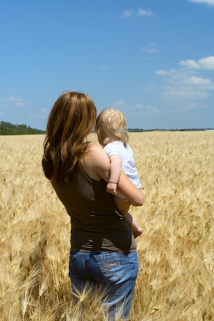 Madre che tiene un bambino al campo di grano