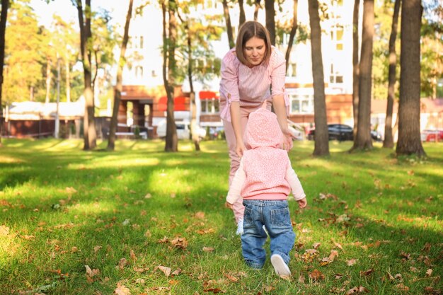 Madre con adorabile bambina che giocano insieme nella sosta di autunno