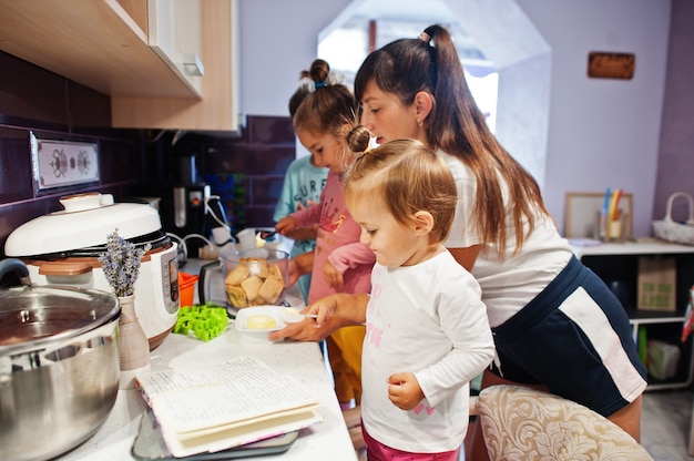 Madre con bambini che cucinano in cucina, momenti felici per bambini.
