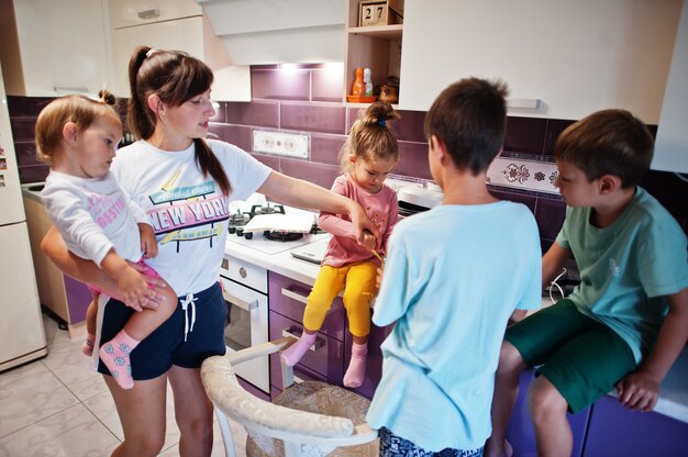 Madre con bambini che cucinano in cucina, momenti felici per bambini.