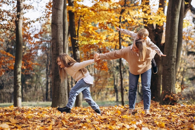 Madre con bambini che si divertono nel parco autunnale