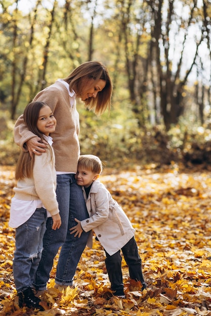 Madre con bambini che si divertono nel parco autunnale